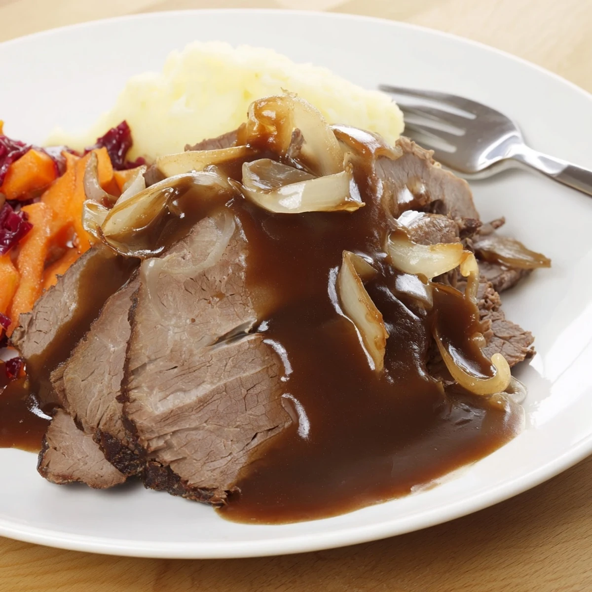Zartes Sauerbraten mit würziger Marinade, serviert mit Rotkohl und Knödeln.