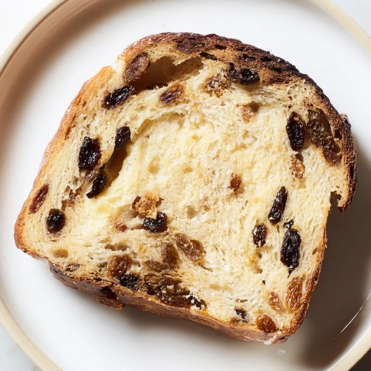 A close-up of a freshly baked Old-Fashioned German Raisin Bread loaf with visible, plump raisins.