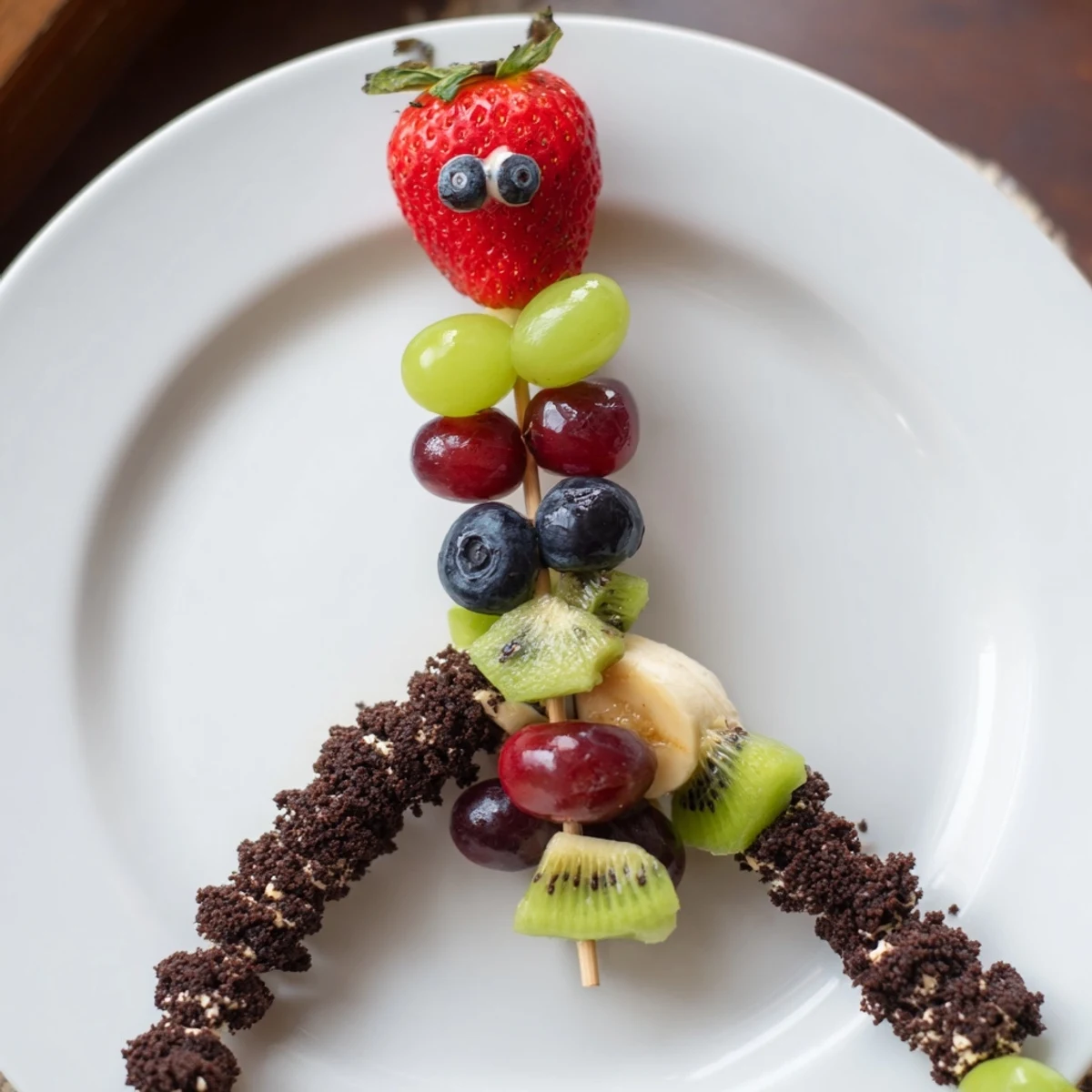 Delicious caterpillar fruit skewer track: a playful, healthy snack with vibrant fruit and cookie crumbs.