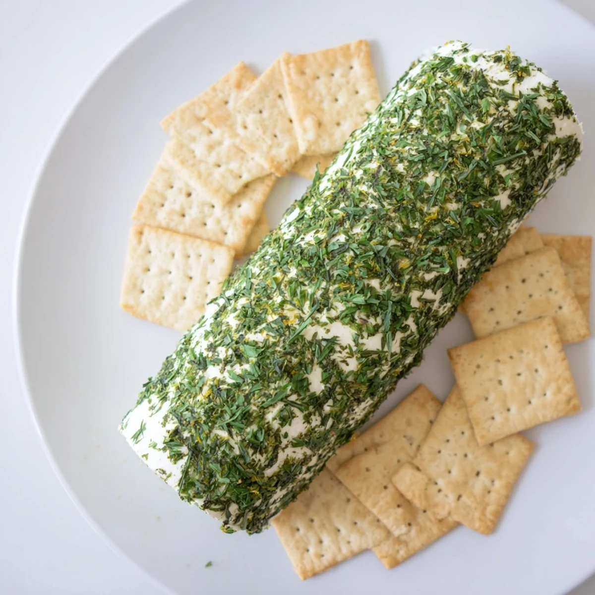 Herb-Coated Cheese Log, creamy and savory, surrounded by a colorful ring of crackers—perfect for the party!