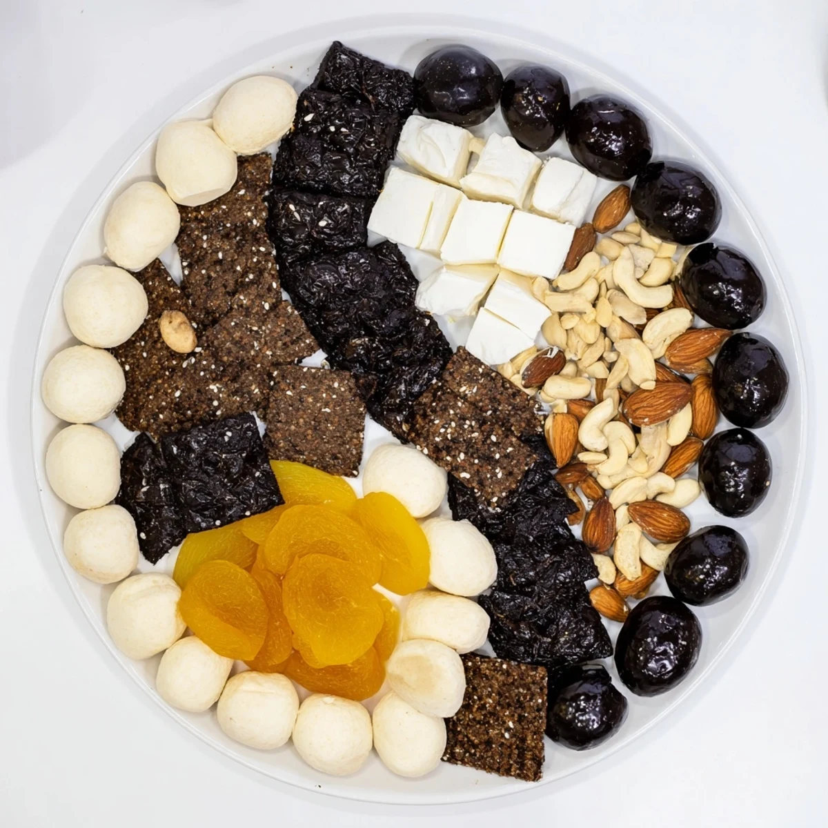 Freshly arranged Yin and Yang balance board features olives, crackers, cheese, and fruit for an amazing snack.