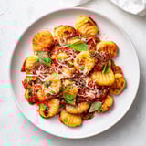A close-up of oven-baked potato gnocchi with tomatoes, mozzarella, and Parmesan, bubbling hot.