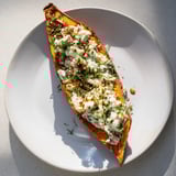 Golden, baked Oven-Baked Sweet Potatoes, split open with a cottage cheese and herb filling, ready to eat.