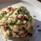 A close-up of fluffy German Bread & Bacon Dumplings, featuring crispy bacon pieces and fresh parsley.