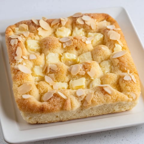 A golden-brown German Butter Cake fresh from the oven, with a glistening sugar and almond topping.