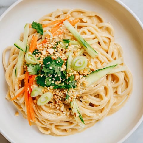 A vibrant bowl of cold sesame noodles, boasting glistening sauce and crunchy toppings.