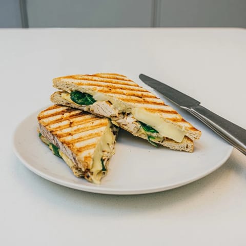 Die warme Grilled Chicken Spinach Panini füllt den Raum mit Duft von Knoblauchbutter und gebratenem Hähnchen.