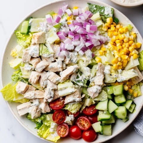 Cremiger Ranch Chicken Chopped Salad mit knusprigem Gemüse und frischen Kräutern auf weißem Teller.  