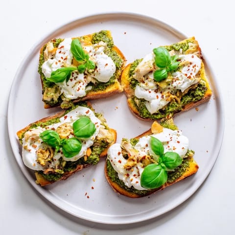 Goldenes Pesto Chicken Burrata Toast auf rustikalem Holztisch, frisch aus dem Ofen.