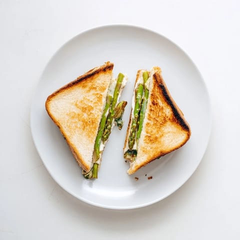 Frisch gegrillte Spargelstangen und cremiger Brie zwischen knusprigem Sauerteigbrot, perfekt für ein saisonales Mittagessen.