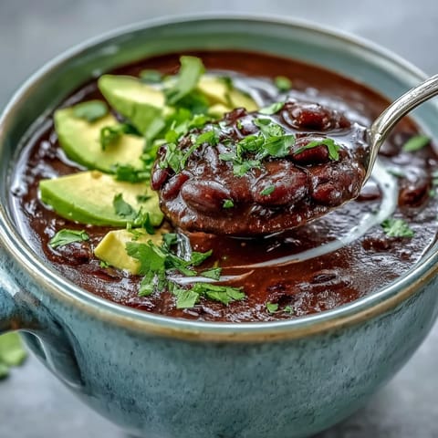 Dieses Black Bean Soup dampft aromatisch in einem Topf, garniert mit frischem Koriander und Avocado.