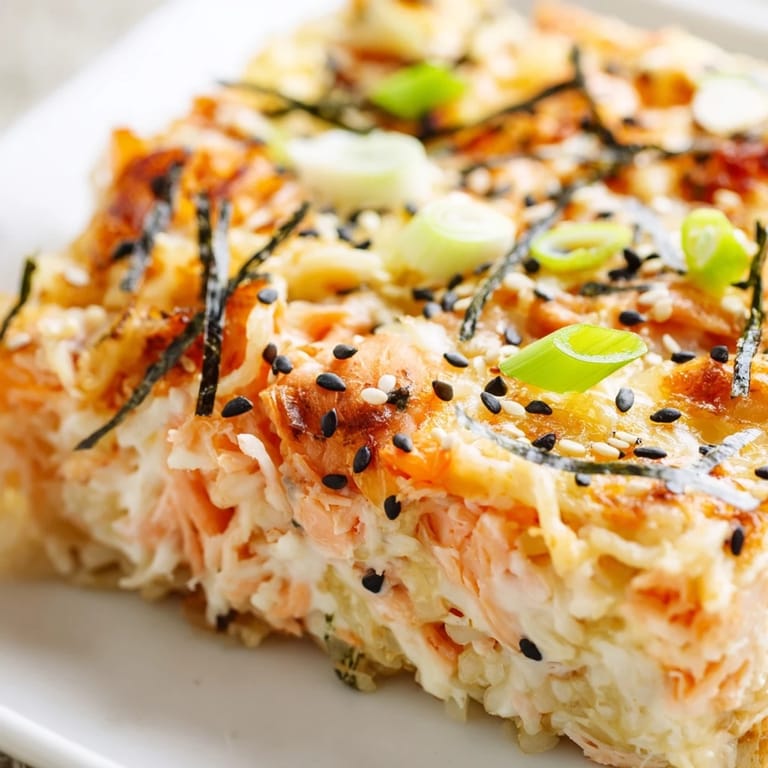 Imagine the bubbly, cheesy topping on this Creamy Salmon Sushi Bake with flaked salmon visible.