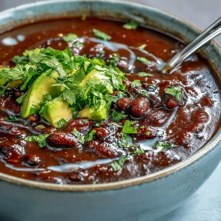 Geschmackvolle Black Bean Soup mit saftigen Tomaten, serviert mit saftigen Limenvierteln und cremigem Vegan Yogurt.