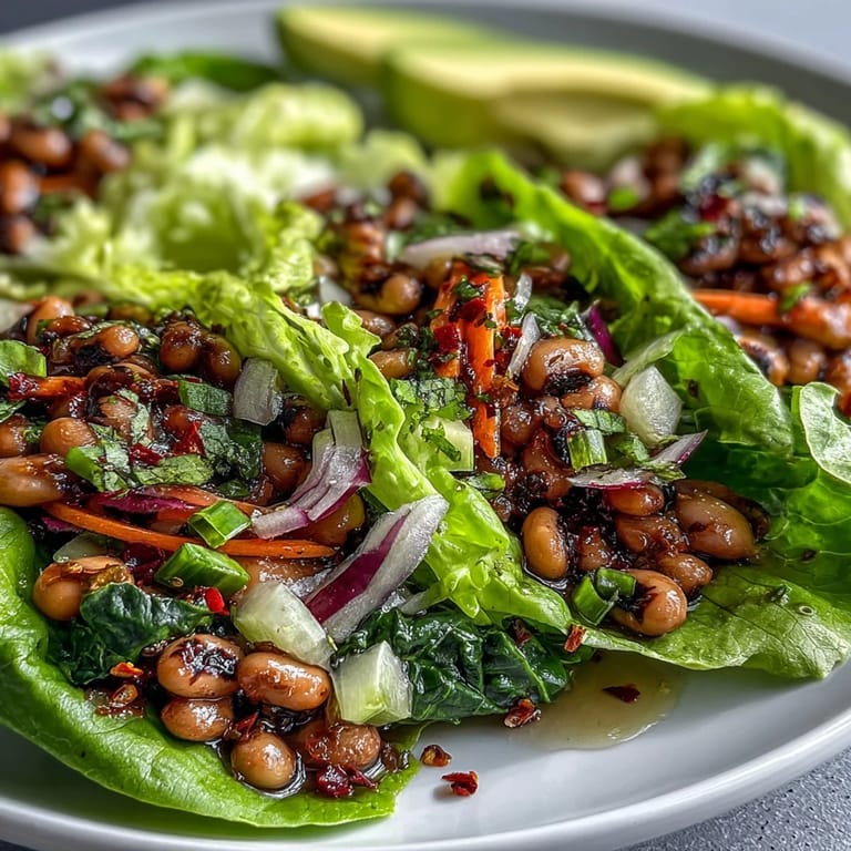 Süße Black-Eyed Pea Lettuce Wraps mit Avocado und Koriander, als proteinreicher Snack auf weißem Teller.